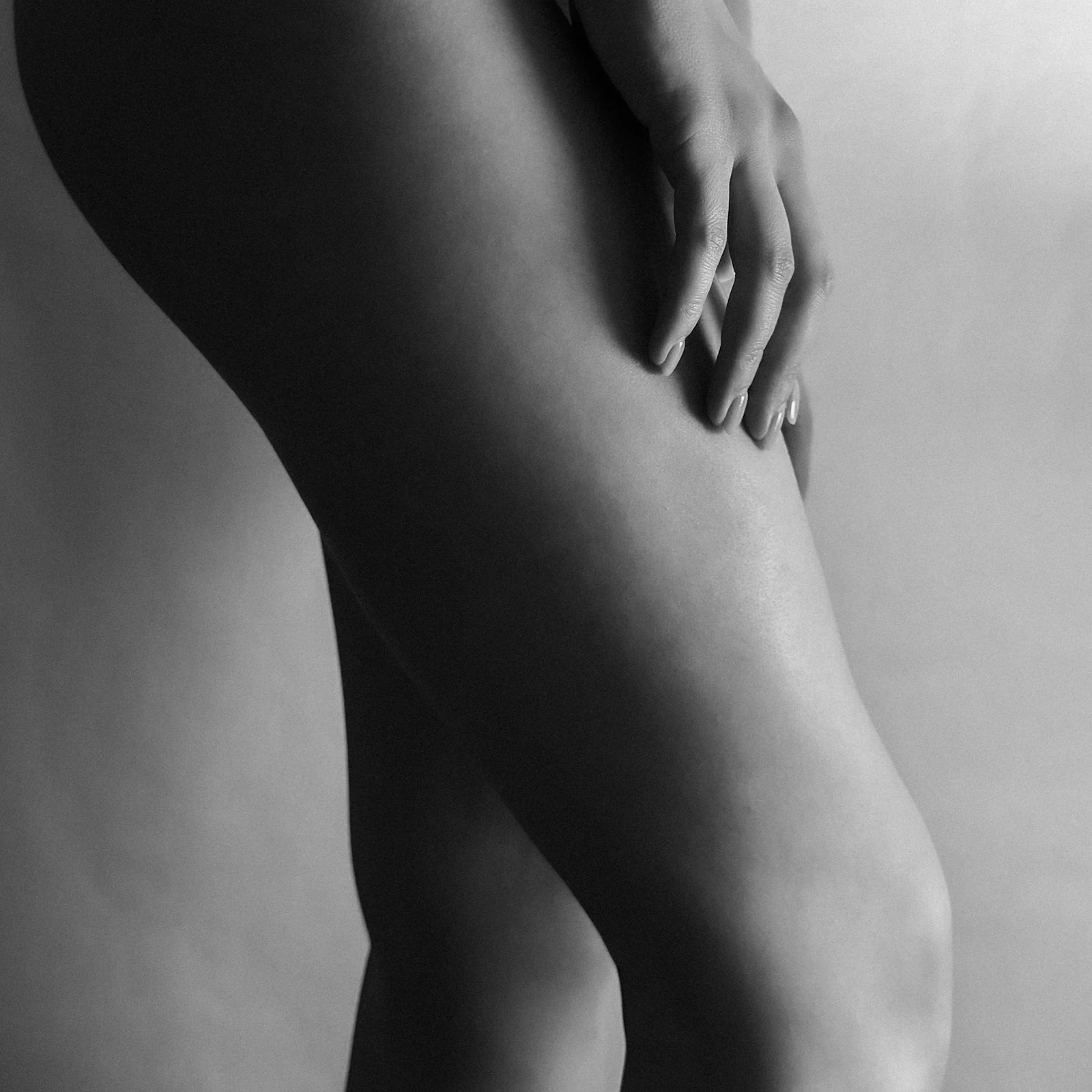 Black-and-white editorial detail of a hand resting on a leg
